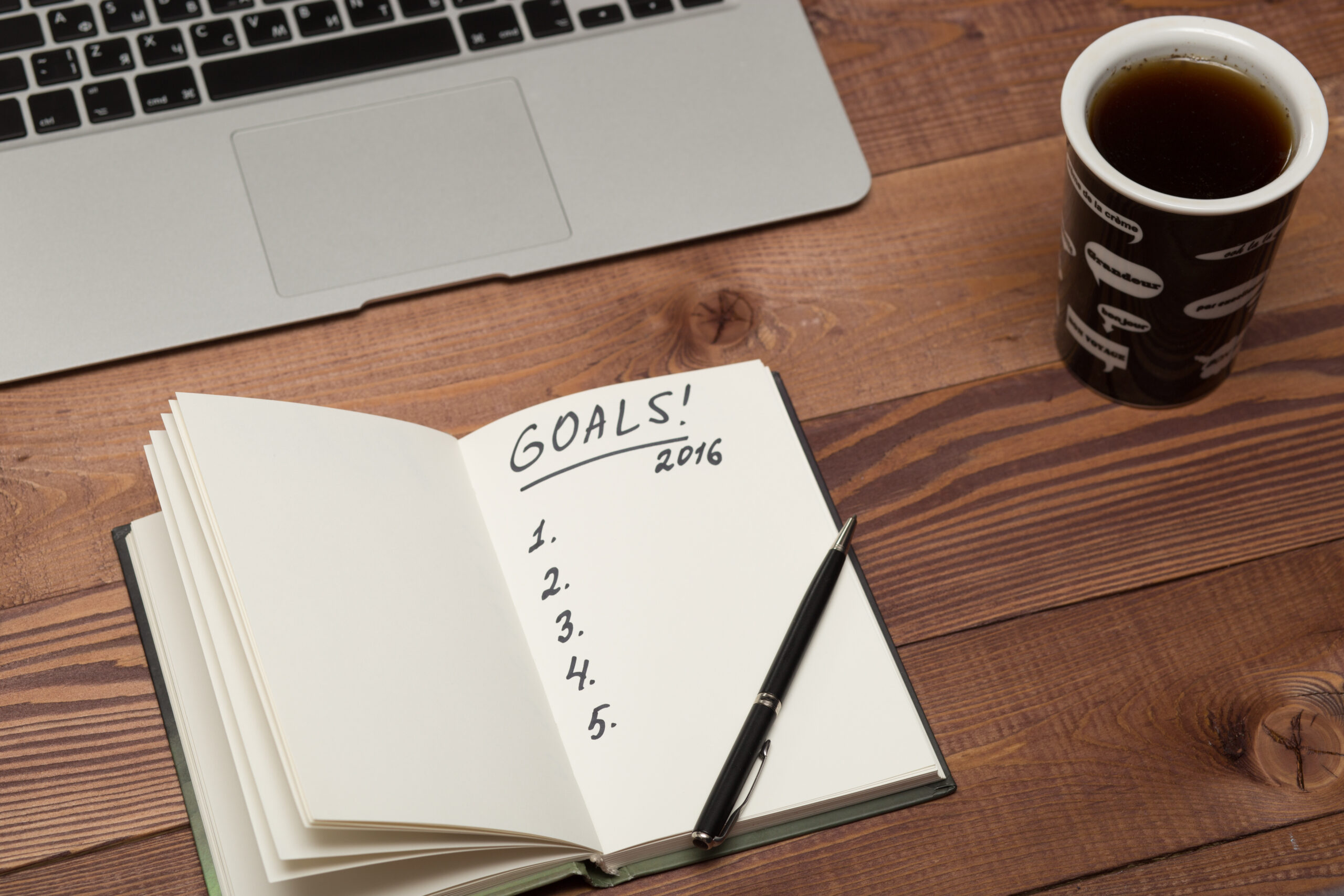 Close-up of a planner on a desk with highlighted goals and a pen, symbolizing strategic planning to overcome procrastination and writer's block.